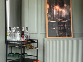 A bar cart with bottles and a mirror in a living room at Cotswolds Castle Sleeps 8 with Enclosed Garden Banbury