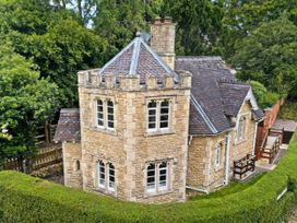 An exterior view of a stone house with multiple windows at Cotswolds Castle Sleeps 8 with Enclosed Garden in Banbury