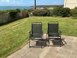 Two chairs on a patio overlooking a garden at Porthleven Coastal Retreat with 5 Bedrooms, Porthleven