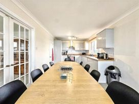 A dining room with a long table and kitchen units at Porthleven Coastal Retreat with 5 Bedrooms Porthleven