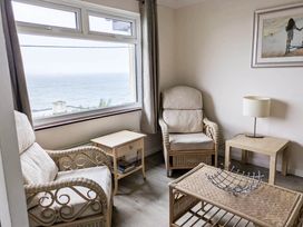 A living room with rattan furniture and a view of the sea at Porthleven Coastal Retreat with 5 Bedrooms Porthleven