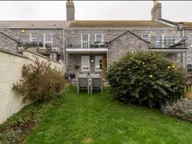 A garden with chairs and a bush at Beautiful Sea Front Cottage in Plymouth