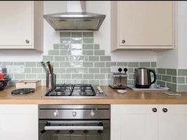 A kitchen with a stove, kettle, toaster, and storage at Beautiful Sea Front Cottage in Plymouth