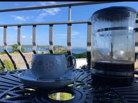 A cup and a french press on a table with an ocean view at Beautiful Sea Front Cottage in Plymouth