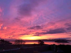 A sunset view over the water with trees and an island at Beautiful Sea Front Cottage in Plymouth