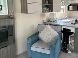 A living room with an armchair and kitchen counter at Caravan in Holcot Sleeps 6 Max 6 people Max 4 adults per booking Pet Friendly Holcot near Moulton