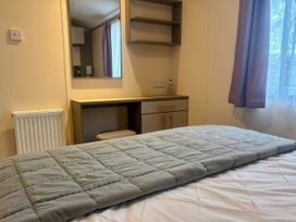 A bedroom with a bed, mirror, and desk at Caravan in Holcot Sleeps 6 Max 6 people Max 4 adults per booking Pet Friendly, Holcot near Moulton