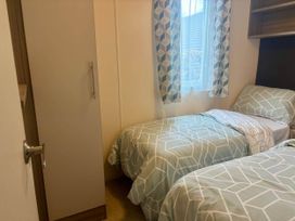 A bedroom with two beds and a wardrobe at Caravan in Holcot Sleeps 6 Max 6 people Max 4 adults per booking Pet Friendly Holcot near Moulton