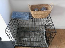A dog crate with a blanket and a woven basket at Aberporth 2 Bed Cottage Sleeps 4 Pet Friendly in Parcllyn near Aberporth