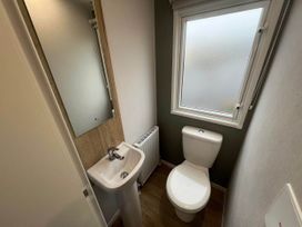 A bathroom with a sink, toilet, and mirror at 8 Guests Swimming Pool 1min to the Beach in Heacham
