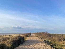 A sandy path surrounded by grass and bushes at 8 Guests Swimming Pool 1min to the Beach Heacham