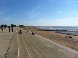 A sandy beach with people walking and sitting at Heacham