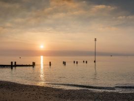 A beach scene with sun setting over the water at 8 Guests Swimming Pool 1min to the Beach Heacham