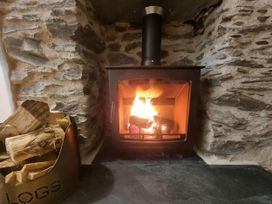 A wood stove with flames and logs in a living room at Looe Cottage Seaside views log fire sleeps 4 Looe