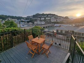 An outdoor seating area with a table and chairs overlooking the harbor at Looe Cottage Seaside views log fire sleeps 4, Looe
