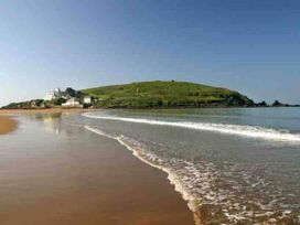 A beach with waves and a hill with buildings at 3Bed Cottage Plymouth Dog friendly Sleeps7, Plymouth