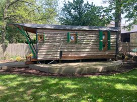A wooden cabin with green shutters and circular windows at The Owl House in countryside setting Near Niwbwrch (newborough)