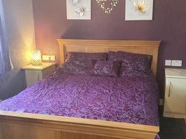 A bedroom with a wooden bed and purple bedding at Fleetwood