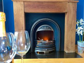 A fireplace with a log fire and glasses in front at Tanygrisiau near Blaenau Ffestiniog