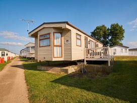 A static caravan with a deck and lawn area at a caravan park