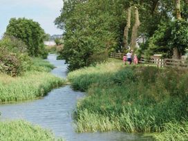 A river with grass and trees alongside a path at a scenic outdoor location