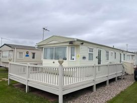 A caravan with a deck and steps at a holiday park near West Mersea