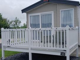 A cabin with a deck and furniture at the property near Flookburgh