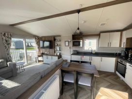 A living room with a sofa and dining area at a holiday home near Flookburgh