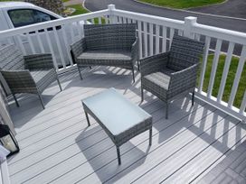 An outdoor patio with gray chairs and a table at The Old Barn in Near Flookburgh
