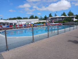 An outdoor swimming pool with flags and buildings at a recreational facility near Flookburgh