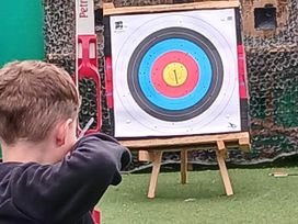 A person aiming at an archery target at an outdoor archery range near Flookburgh