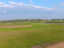 A grassy area with a flag and hill in the background near Flookburgh