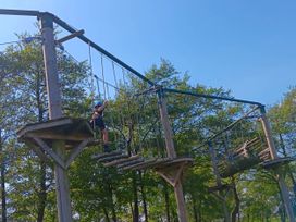 A child navigating a ropes course near trees
