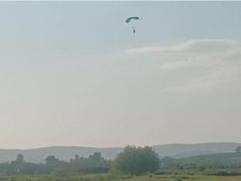 A paraglider flying in the sky with a landscape background near Flookburgh