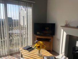 A living room with a television and a table with flowers at The Old Barn in Bridlington