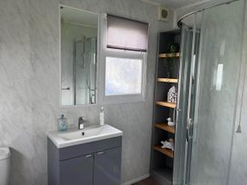 A bathroom with a sink, mirror, toilet and shower at The Old Barn in Bridlington