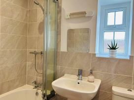 A bathroom with a shower, bathtub, sink, and window at Nebo near Penygroes