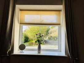 A window with a flower vase and a mirror at a property in Nebo near Penygroes