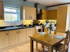 A kitchen with wooden cabinets and a dining table at the property in Nebo near Penygroes