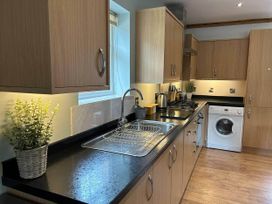 A kitchen with cabinets, sink, stove and washing machine at a property in Nebo near Penygroes