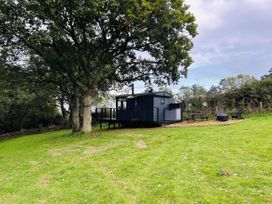 A hut with a deck and seating area surrounded by grass at a property in Newton Abbot