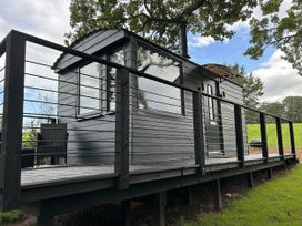A cabin with a deck and railing at a property in Newton Abbot