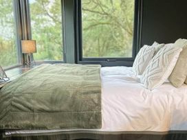 A bed with pillows and a blanket near a window at The Old Barn in Newton Abbot