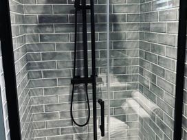 A shower with tiles and a glass door at The Old Barn in Newton Abbot