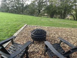An outdoor area with a fire pit and wooden chairs in Newton Abbot