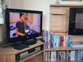 A living room with a television, DVD player, and shelves of books and DVDs at the property