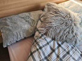 A bed with pillows and a plaid blanket in a bedroom