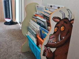 A bookshelf with children's books and an illustrated character at a reading nook