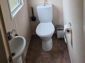 A bathroom with a toilet, sink, and towel at The Old Barn in 