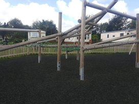 A climbing frame in an outdoor playground with caravans in the background